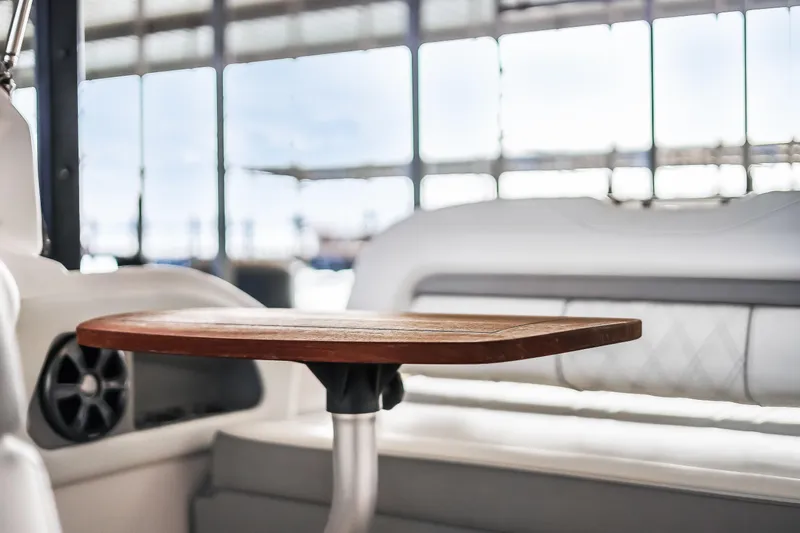 Tarini Yacht Photos Pics Interior of 2020 Regal 28 Express boat with wooden table and cushioned seating.