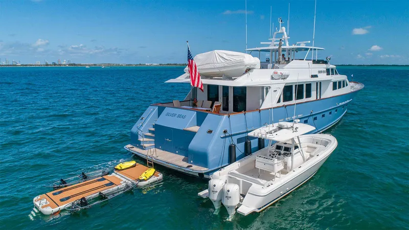 Silver Seas Yacht Photos Pics Luxurious 1998 Burger Raised Pilothouse yacht with tender and paddleboards in serene blue waters.
