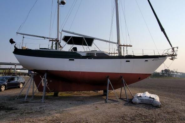 1981 Hardin 45 Voyager sailboat on stands, with dinghy nearby, in a boatyard setting.