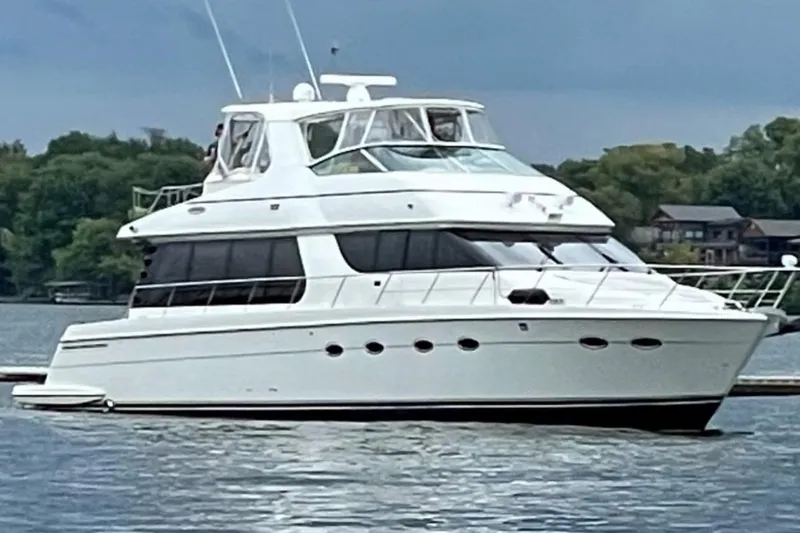 Flying Lady Yacht Photos Pics 2004 Carver 570 Voyager Pilothouse yacht on a serene lake with lush greenery.