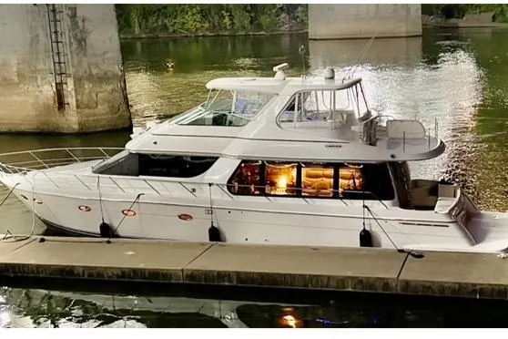 Flying Lady Yacht Photos Pics 2004 Carver 570 Voyager Pilothouse yacht docked at night, illuminated interior, serene water reflection.