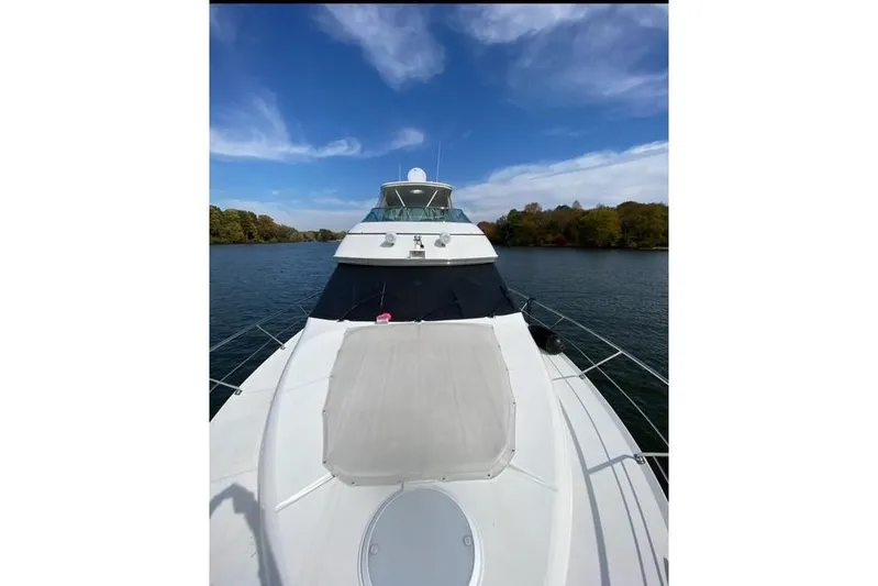 Flying Lady Yacht Photos Pics 2004 Carver 570 Voyager Pilothouse yacht cruising on a serene river under a clear blue sky.