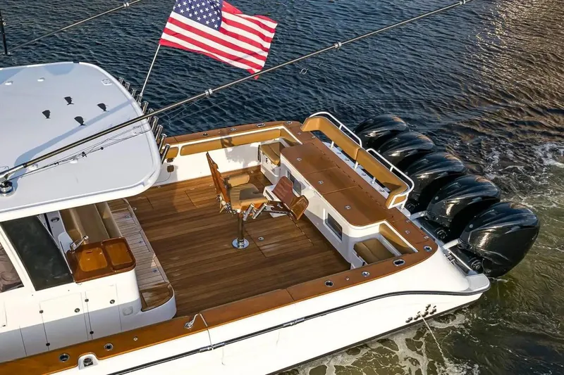 Next To Sell Yacht Photos Pics 2020 HCB Estrella boat with American flag, spacious deck, and multiple outboard engines.