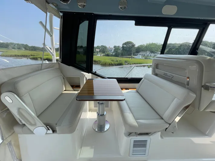 Sea Cure Yacht Photos Pics Interior of 2021 Boston Whaler 405 Conquest with seating and table, overlooking scenic waterway.