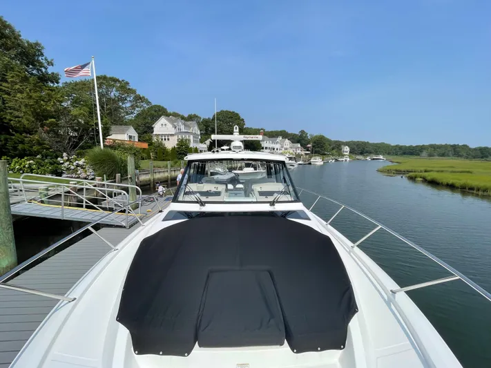 Sea Cure Yacht Photos Pics Boston Whaler 405 Conquest 2021 docked by a scenic riverside with houses and greenery.