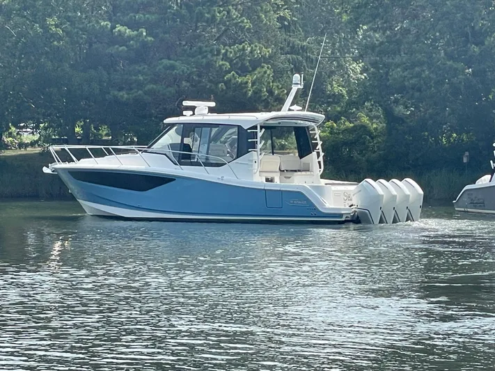Sea Cure Yacht Photos Pics 2021 Boston Whaler 405 Conquest boat on calm water, surrounded by trees.