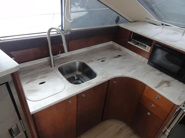  Yacht Photos Pics 2009 Meridian 441 Sedan yacht kitchen with sink, microwave, and wooden cabinetry.