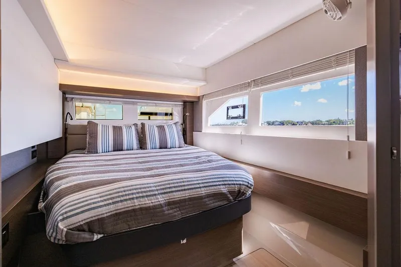 Nautilus Yacht Photos Pics Luxurious bedroom interior of 2021 Leopard 53 Powercat yacht with striped bedding and large windows.
