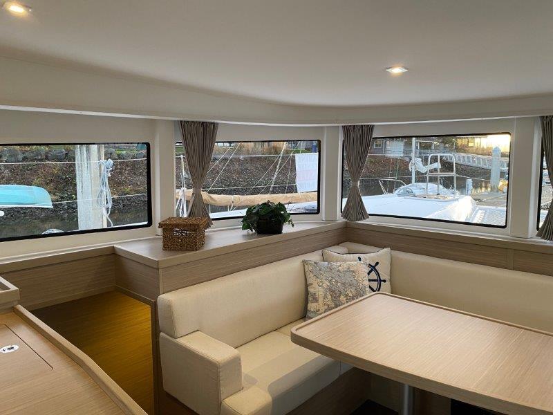 Interior of 2024 Lagoon 42 catamaran with modern seating and large windows.