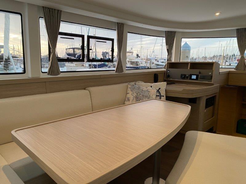Interior of 2024 Lagoon 42 catamaran with dining table and marina view.