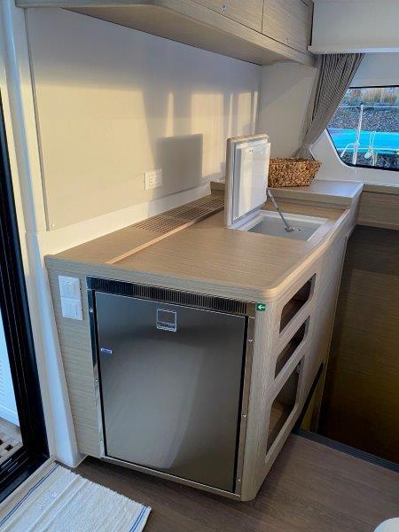 Modern kitchen area in 2024 Lagoon 42 catamaran with stainless steel fridge and sink.