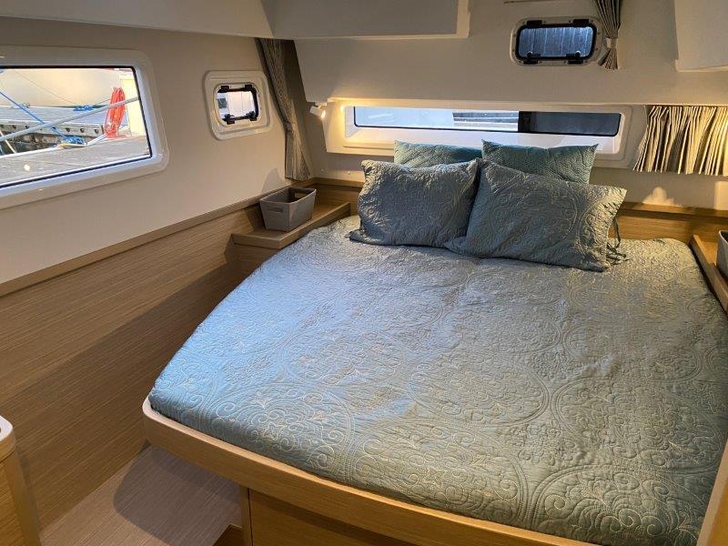 2024 Lagoon 42 catamaran bedroom with double bed, windows, and modern decor.