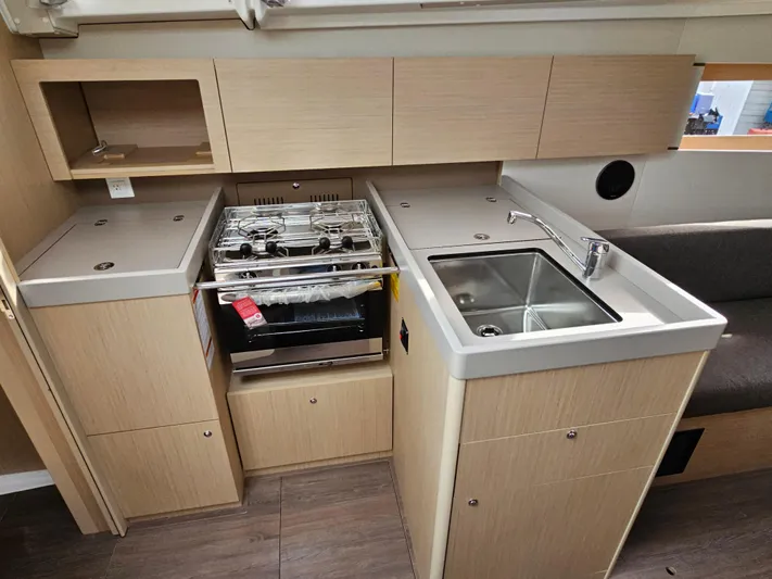  Yacht Photos Pics Modern kitchen in 2024 Beneteau Oceanis 38.1 yacht with stove, sink, and storage cabinets.