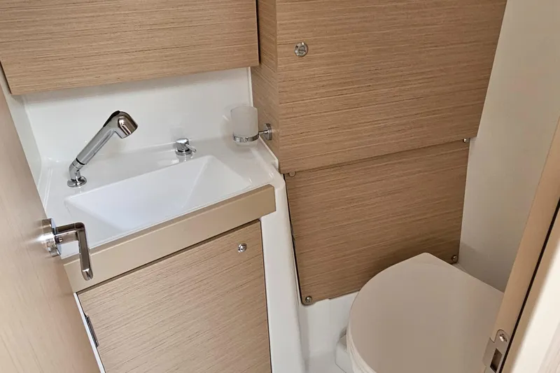  Yacht Photos Pics Compact bathroom in 2024 Beneteau Oceanis 38.1 yacht with modern fixtures and wood accents.