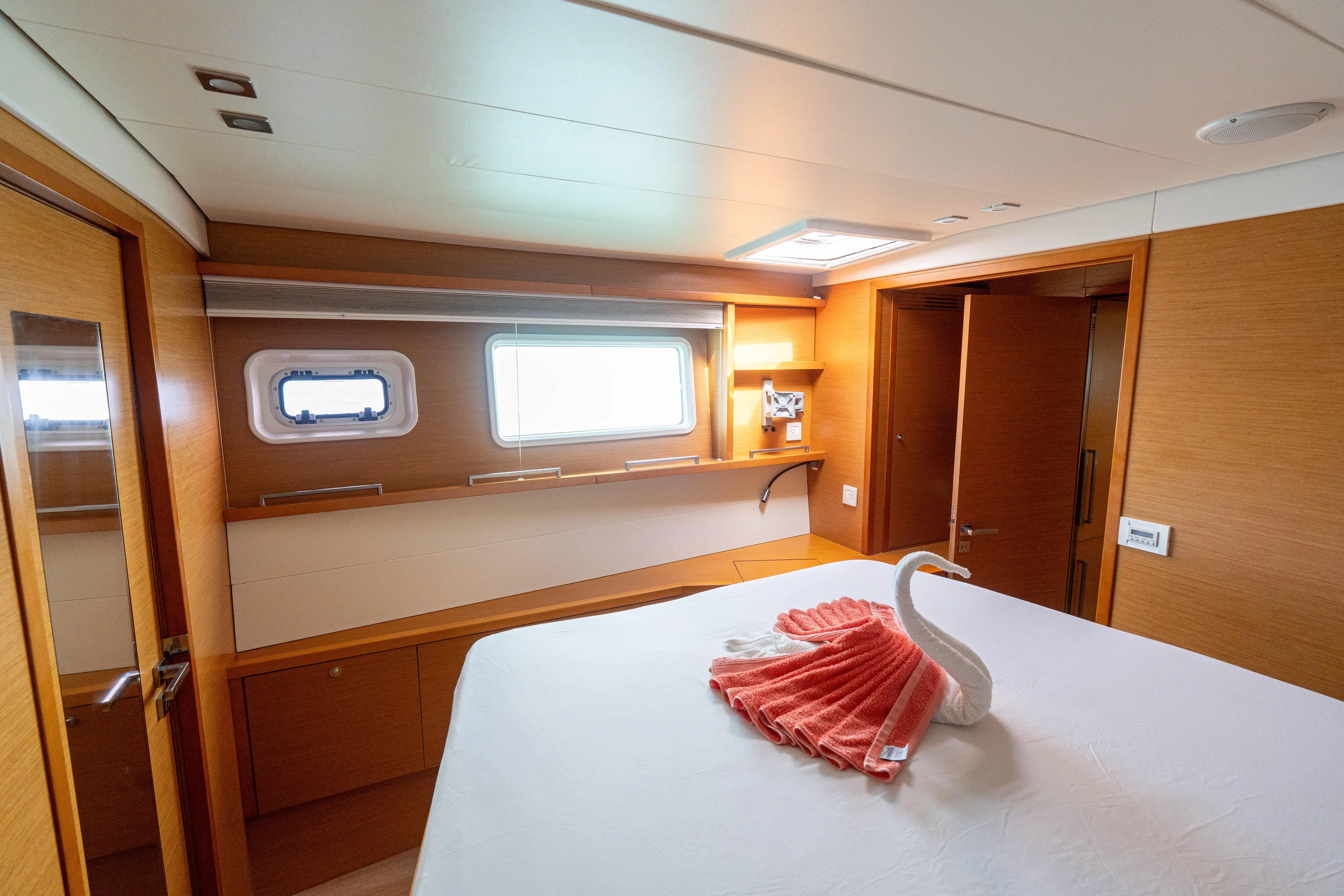 LibertÉ Yacht Photos Pics Luxurious cabin interior of 2011 Lagoon 560 yacht with elegant wood finish and decorative towel swan.