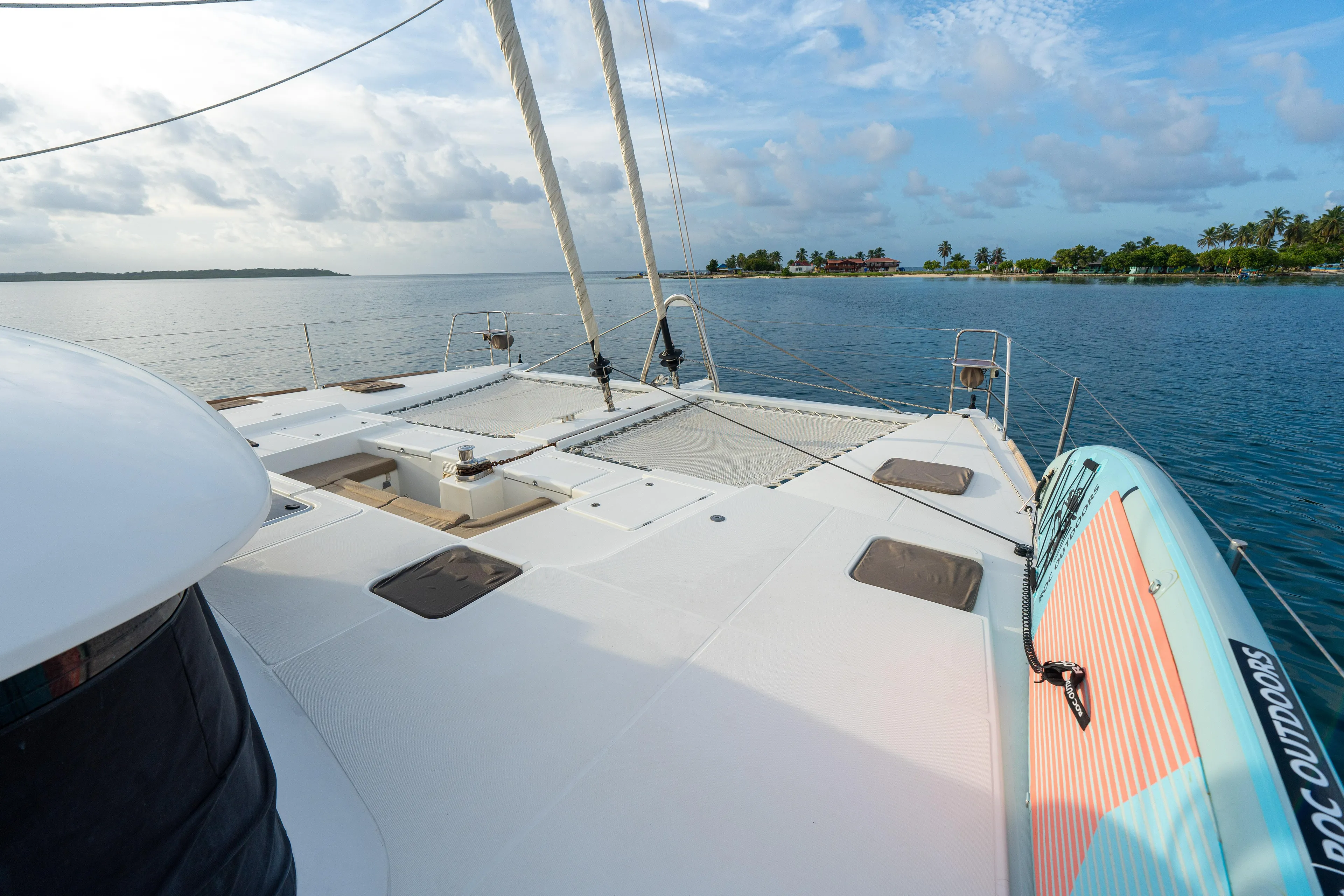 LibertÉ Yacht Photos Pics Lagoon 560 catamaran deck with paddleboard, anchored near tropical island, 2011 model.