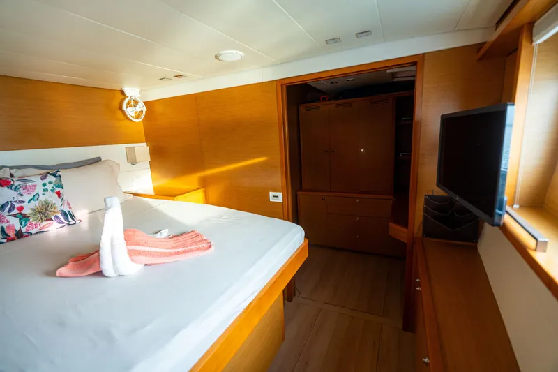 LibertÉ Yacht Photos Pics Luxurious cabin interior of 2011 Lagoon 560 yacht with bed, TV, and wooden decor.