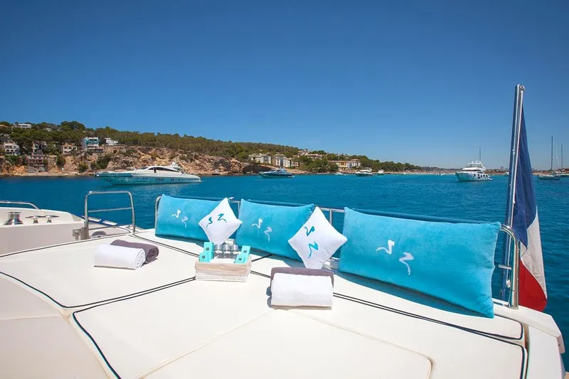 Froggy Yacht Photos Pics Luxurious Sunseeker Predator 82 yacht deck with blue cushions, towels, and scenic ocean view.