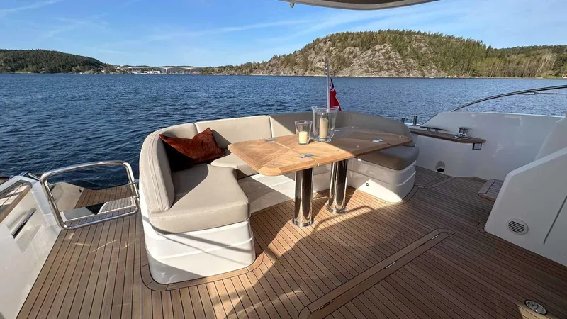 F65012 Yacht Photos Pics Luxurious 2024 Princess F65 yacht deck with seating, table, and scenic water view.
