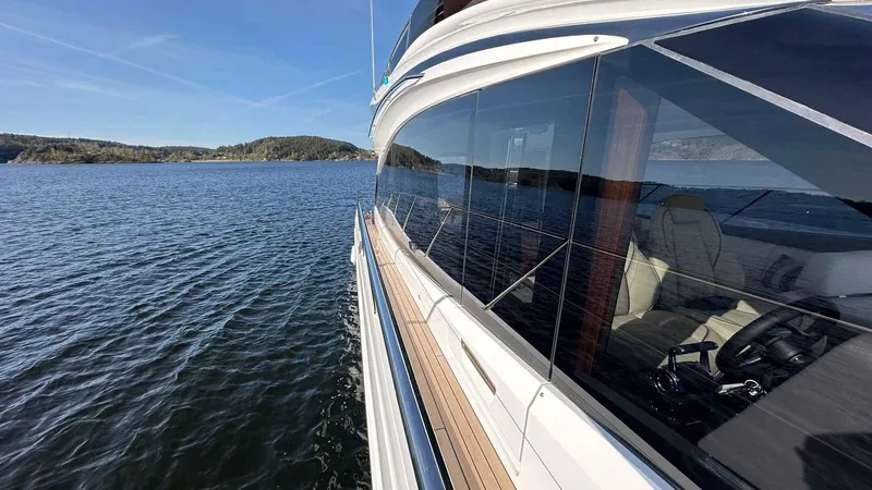 F65012 Yacht Photos Pics 2024 Princess F65 yacht cruising on a serene lake with clear blue skies.
