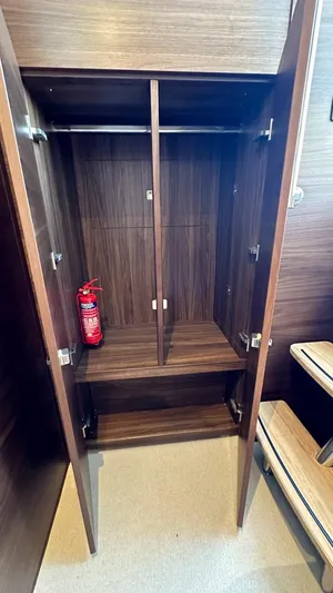 F65012 Yacht Photos Pics 2024 Princess F65 yacht interior closet with fire extinguisher, wooden finish.