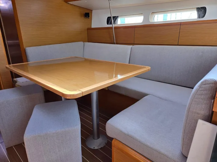  Yacht Photos Pics Interior of 2012 Jeanneau Sun Odyssey 439 yacht with wooden table and gray seating.