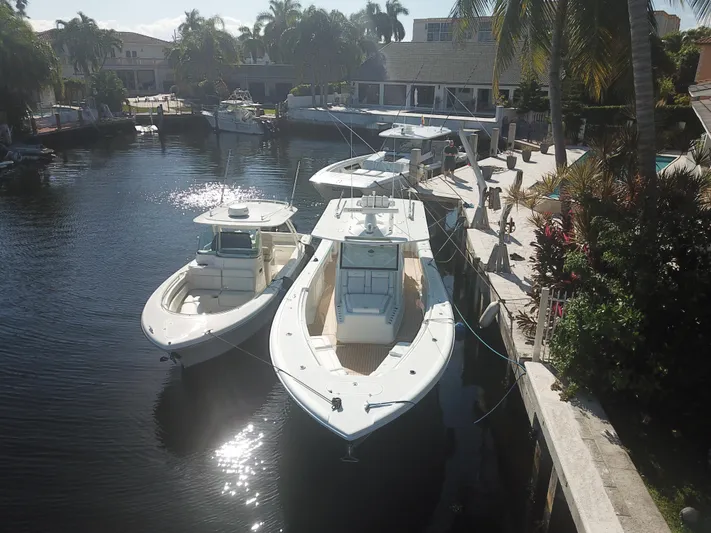  Yacht Photos Pics 2018 Yellowfin 42 boats docked in a sunny canal, surrounded by palm trees.