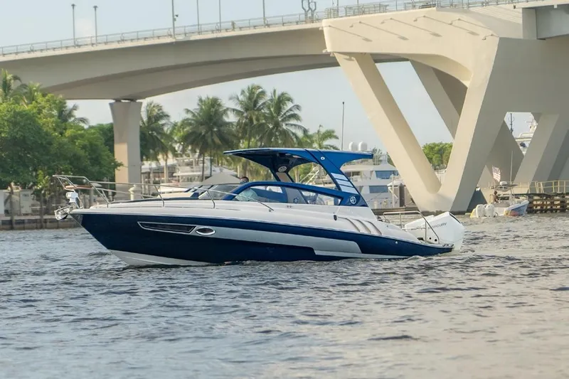  Yacht Photos Pics 2024 Hanover 305 White & Blue Edition boat cruising under a bridge with palm trees.