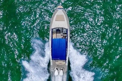  Yacht Photos Pics Aerial view of 2024 Hanover 305 White & Blue Edition boat cruising on vibrant green water.