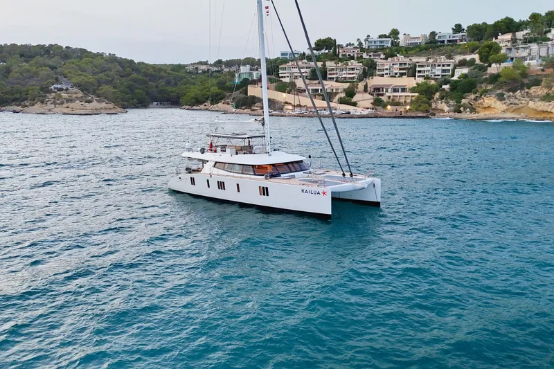 Kailua Yacht Photos Pics Luxurious 2018 Sunreef 74 catamaran sailing near a scenic coastal landscape.