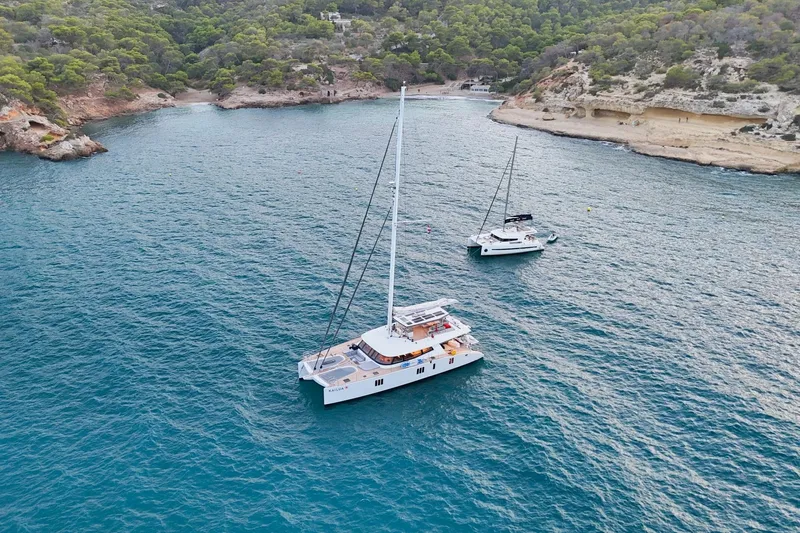 Kailua Yacht Photos Pics Two Sunreef 74 catamarans anchored in a scenic coastal bay, 2018 model.