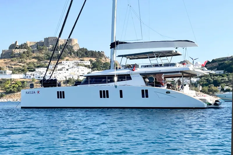 Kailua Yacht Photos Pics Luxury Sunreef 74 catamaran sailing near a scenic coastal town, 2018 model.