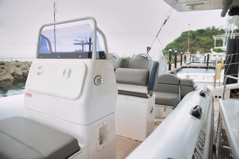 Kailua Yacht Photos Pics 2018 Sunreef 74 yacht deck with seating and helm, docked near rocky shoreline.