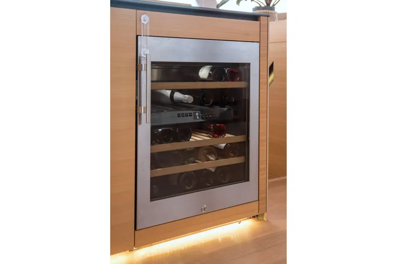 Kailua Yacht Photos Pics Wine cooler on 2018 Sunreef 74 yacht, featuring wooden shelves and glass door.
