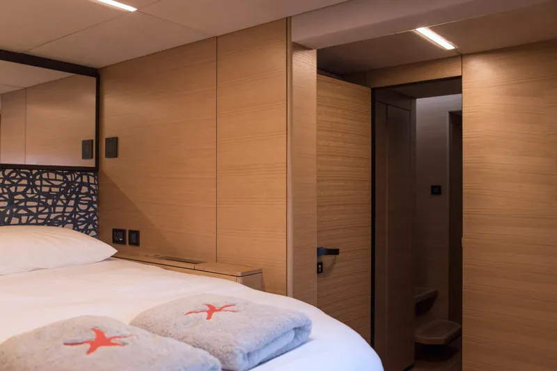 Kailua Yacht Photos Pics Luxurious Sunreef 74 yacht bedroom interior, 2018 model, featuring modern wood paneling and cozy bedding.