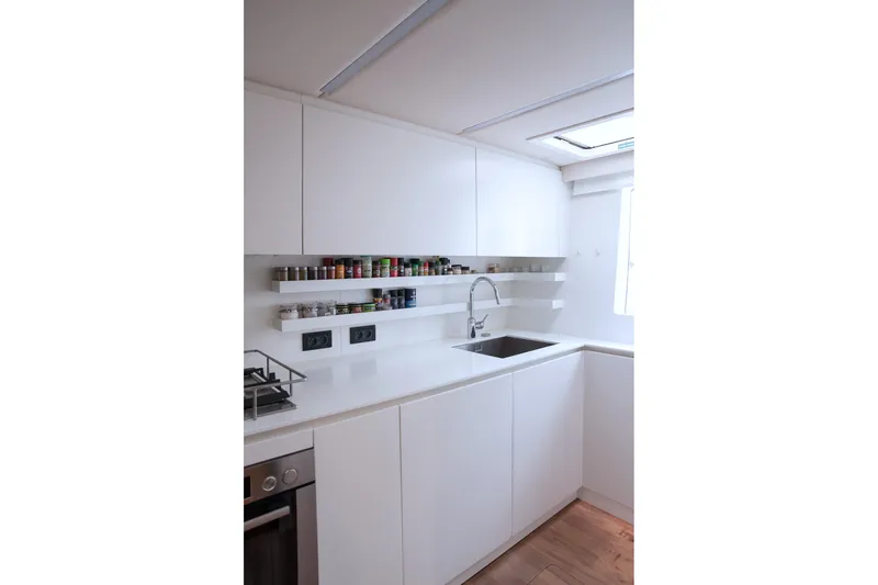 Kailua Yacht Photos Pics Modern white kitchen interior on 2018 Sunreef 74 yacht, featuring sleek cabinetry and spice shelves.