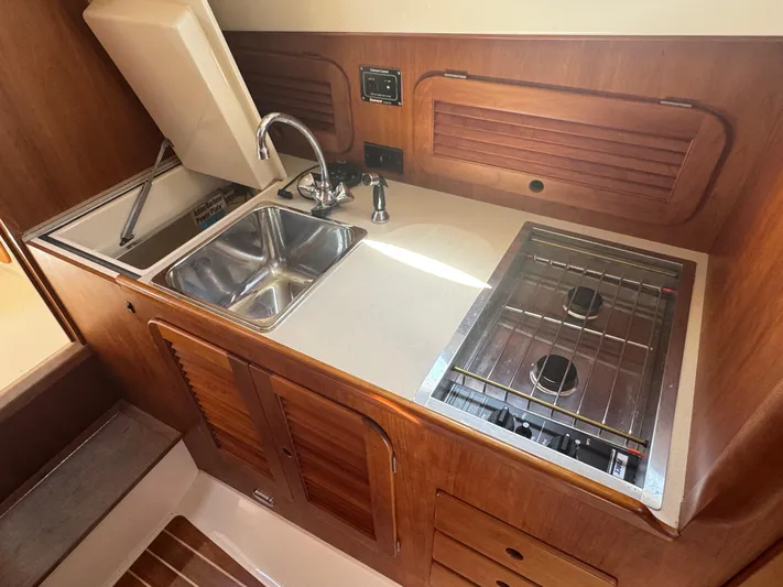Tamarack Yacht Photos Pics 1999 Hinckley Picnic yacht kitchen with sink, stove, and wooden cabinetry.