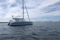 Custom CATAMARAN 12.30 M, 2003 model, sailing near a lighthouse under a cloudy sky.
