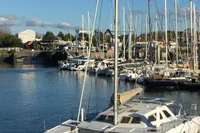 A marina with various sailboats, including a 2003 Custom CATAMARAN 12.30 M, under a clear blue sky.