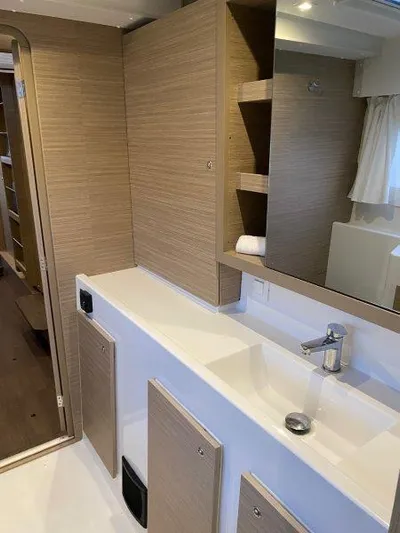 Yacht Photos Pics Modern bathroom interior of 2024 Lagoon 42 catamaran with sleek wooden cabinets and white sink.