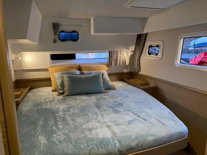  Yacht Photos Pics Luxurious bedroom interior of 2024 Lagoon 42 catamaran with cozy bedding and ample natural light.