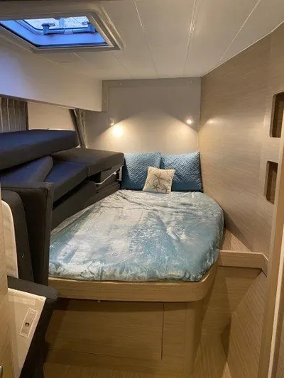  Yacht Photos Pics Modern bedroom interior of 2024 Lagoon 42 catamaran with skylight and cozy bedding.