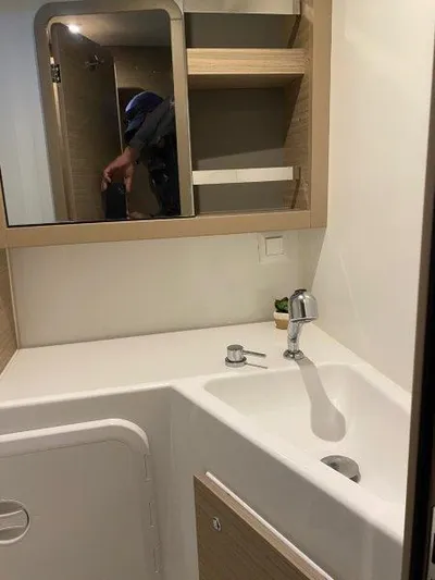  Yacht Photos Pics Modern bathroom in 2024 Lagoon 42 catamaran with sink, mirror, and storage shelves.