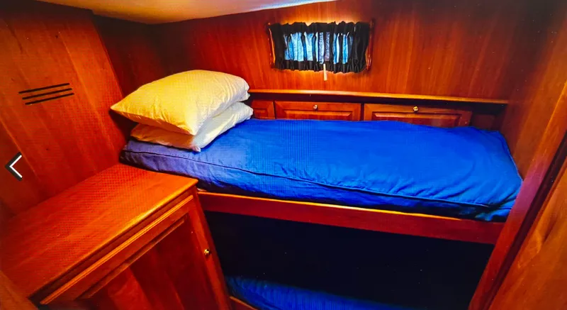 Edmond Dantes Yacht Photos Pics Cozy cabin interior of 2004 Legacy Downeast boat with wooden furnishings and blue bedding.