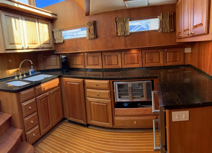 Edmond Dantes Yacht Photos Pics Luxurious 2004 Legacy Downeast yacht kitchen with wooden cabinetry and black countertops.