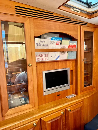 Edmond Dantes Yacht Photos Pics Wooden interior of 2004 Legacy Downeast boat with TV, books, and glass cabinets.