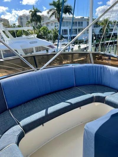 Edmond Dantes Yacht Photos Pics 2004 Legacy Downeast boat with blue seating, docked near palm trees and buildings.