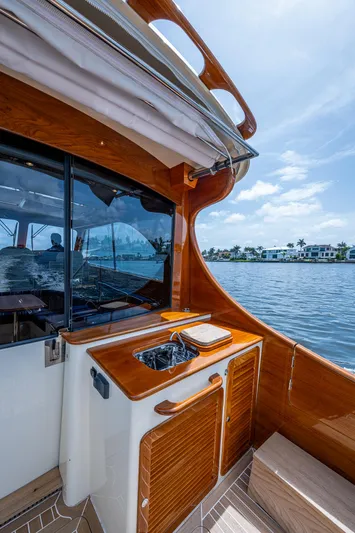  Yacht Photos Pics Hinckley Talaria 43 Motoryacht 2021, elegant wood finish, docked by waterfront homes.