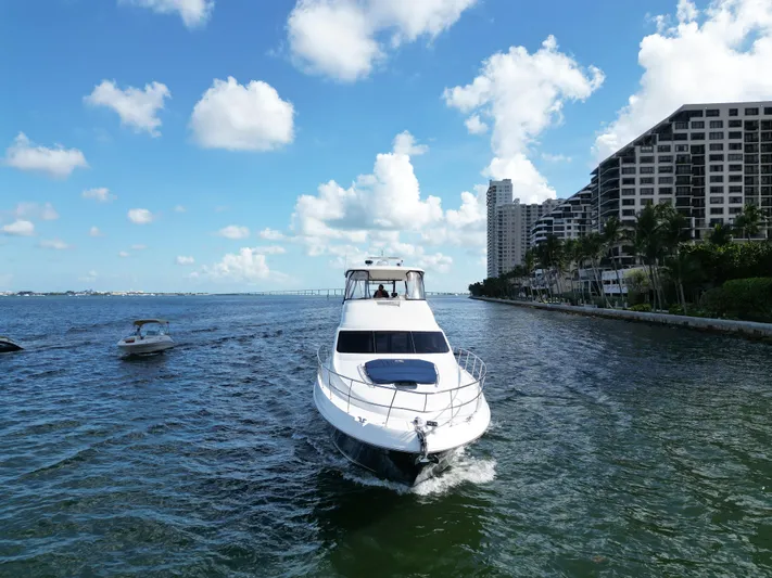  Yacht Photos Pics 2005 Sea Ray 58 Sedan Bridge yacht cruising near coastal buildings under blue sky.