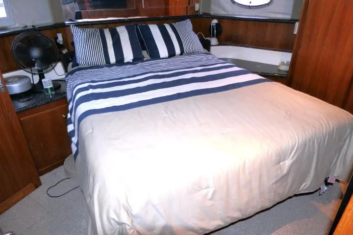 Code Four Yacht Photos Pics Cozy bedroom in 2000 Carver 406 Motor Yacht with striped bedding and wooden accents.